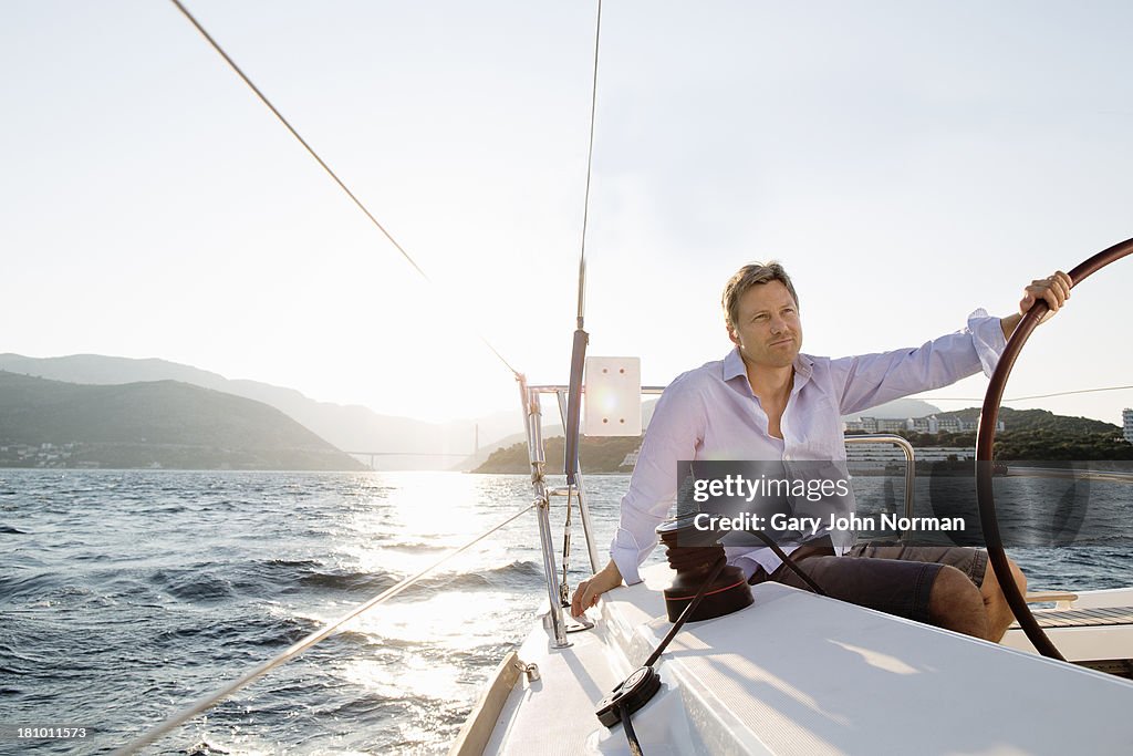 Man sitting at stern holding wheel in one hand