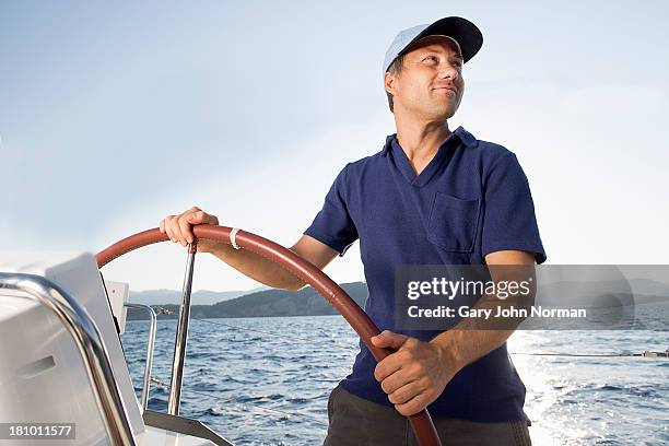 man at hem of sailing yacht - boat helm stock pictures, royalty-free photos & images