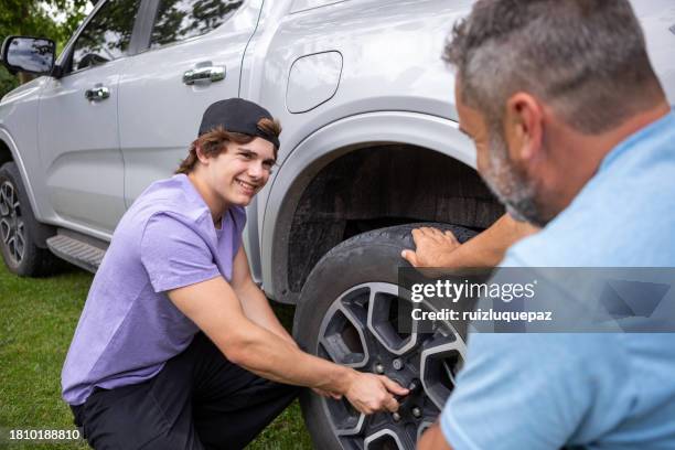 father taught his teenage son how to change a car tire - man with tire iron stock pictures, royalty-free photos & images
