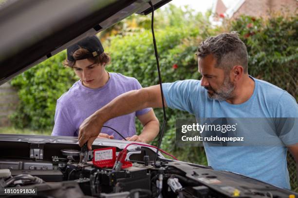 father taught his teenage son how to repair the car - car battery stock pictures, royalty-free photos & images