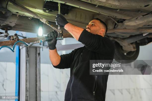 man is working under the car in auto service. - car suspension stock pictures, royalty-free photos & images