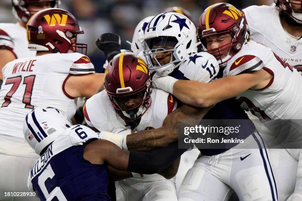 Brian Robinson Jr. #8 of the Washington Commanders is tackled by Donovan Wilson and Micah Parsons of the Dallas Cowboys during the first quarter at...