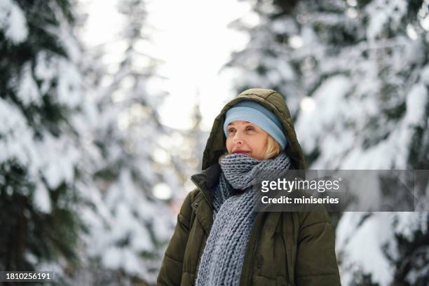 portrait of a beautiful woman enjoying a walk in the forest on a cold winter day - middle aged woman winter stockfoto's en -beelden
