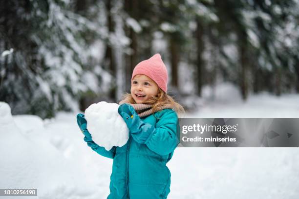 portrait of pretty little girl playing with the snow on a cold winter day - snow day stock pictures, royalty-free photos & images