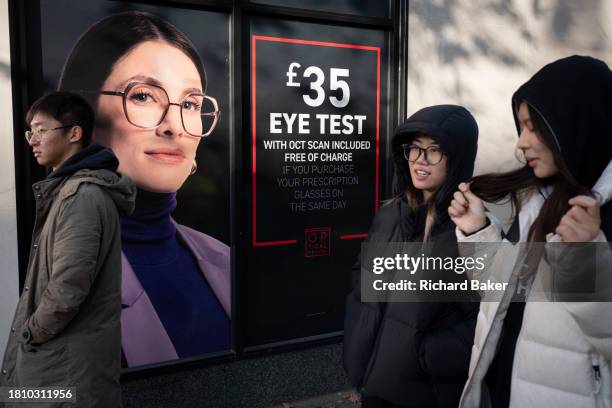 As potential customers walk-by, an optician's billboard shows a model wearing the perfect pair of glasses, on 29th November 2023, in London, England.