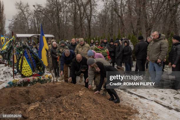 Relatives and friends toss handfuls of soil over the coffin during the funeral service of Ukrainian serviceman Sergiy Pavlichenko, who was killed...