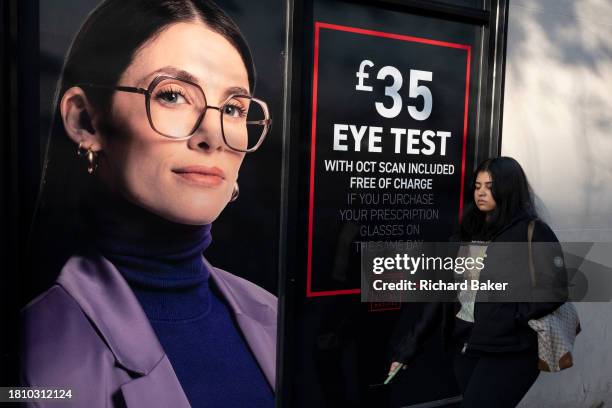 As potential customers walk-by, an optician's billboard shows a model wearing the perfect pair of glasses, on 29th November 2023, in London, England.