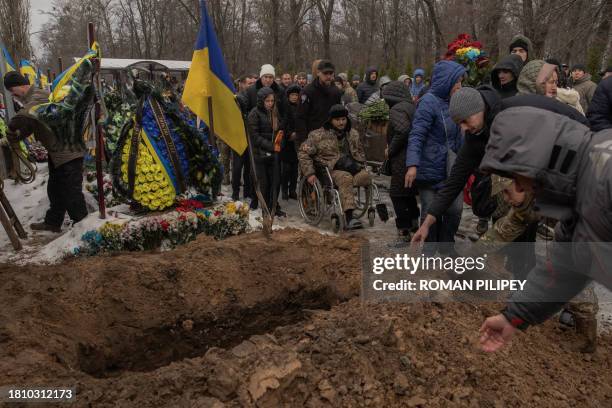 Relatives and friends toss handfuls of soil over the coffin during the funeral service of Ukrainian serviceman Sergiy Pavlichenko, who was killed...