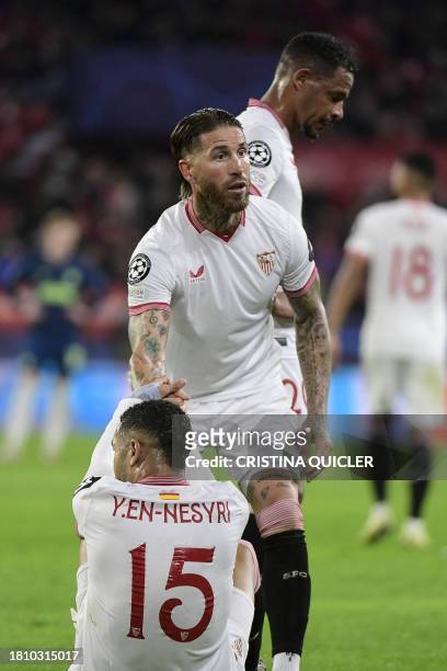 Sevilla's Moroccan forward Youssef En-Nesyri is helped by Sevilla's Spanish defender Sergio Ramos to stand up during the UEFA Champions League first...