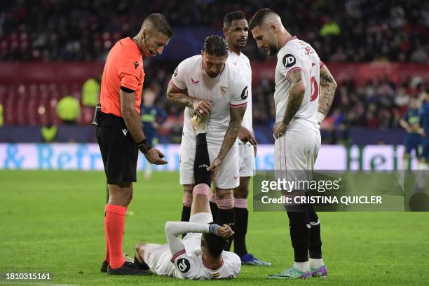 Italian referee Davide Massa checks on Sevilla's Moroccan forward Youssef En-Nesyri as Sevilla's Spanish defender Sergio Ramos helps him stretching...
