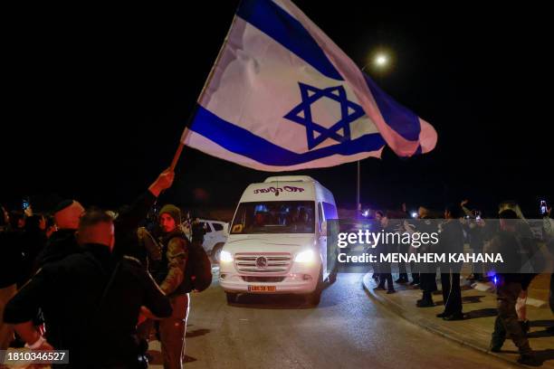 Man waves an Israeli flag as a vehicle carrying two Israeli-Russian hostages, taken by Hamas militants on the October 7 attak and released on...