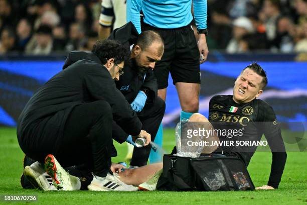 Napoli's Polish midfielder Piotr Zielinski receives medical attention after resulting injured during the UEFA Champions League first round group C...