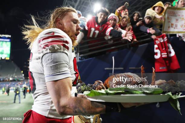 George Kittle of the San Francisco 49ers walks off the field with a turkey after beating the Seattle Seahawks 31-13 at Lumen Field on November 23,...