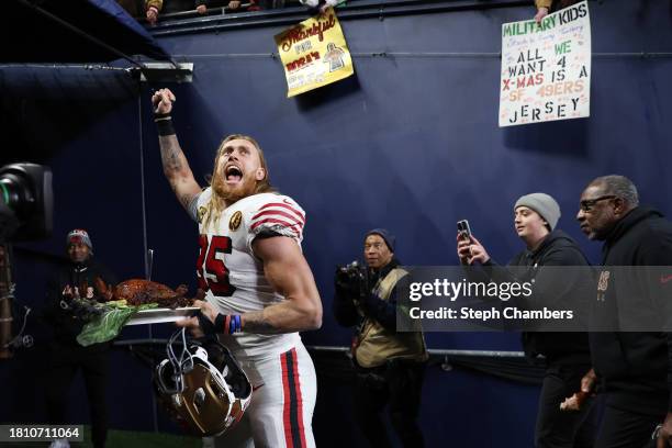 George Kittle of the San Francisco 49ers walks off the field with a turkey after beating the Seattle Seahawks 31-13 at Lumen Field on November 23,...