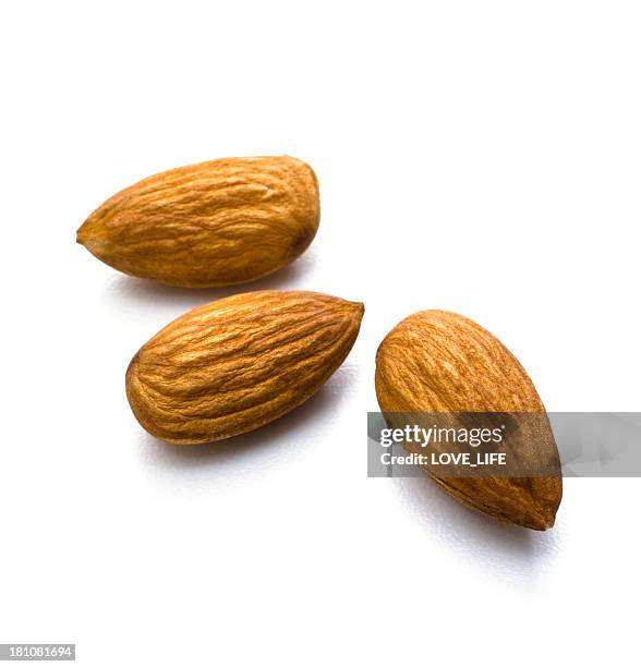 arrangement of three almonds against white background - almond stock pictures, royalty-free photos & images