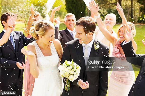 gli ospiti lanciare coriandoli e stelle filanti su coppia durante la reception in giardino - cerimonia di nozze foto e immagini stock