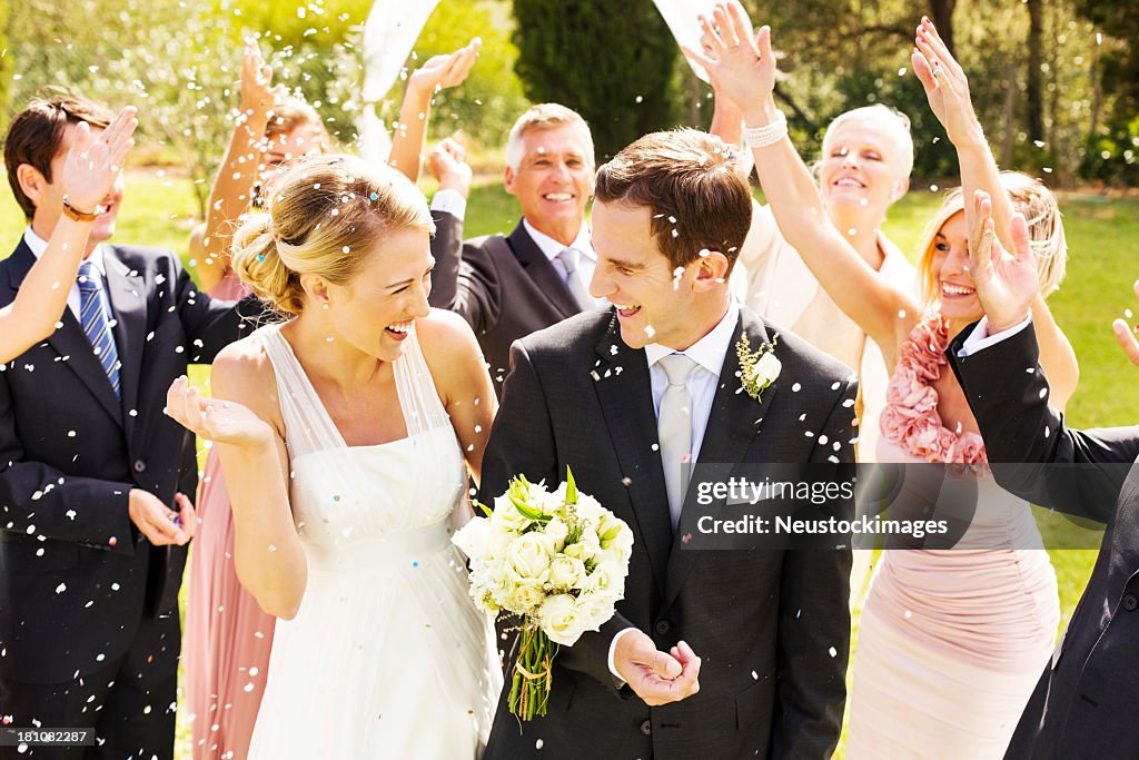 Guests Throwing Confetti On Couple During Reception In Garden