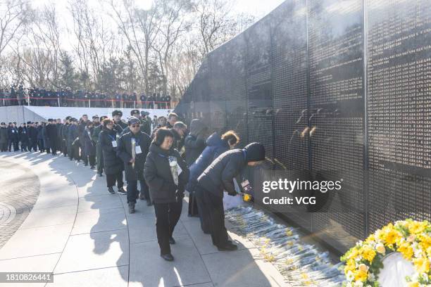 Attendees lay flowers during a burial ceremony for the remains of 25 Chinese soldiers who died during the Korean War at the Chinese People's...