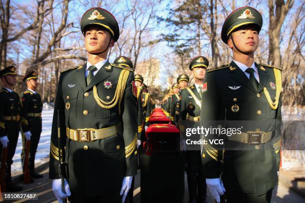 Chinese honour guards carry coffins containing remains of 25 Chinese soldiers who died during the Korean War during a burial ceremony at the Chinese...