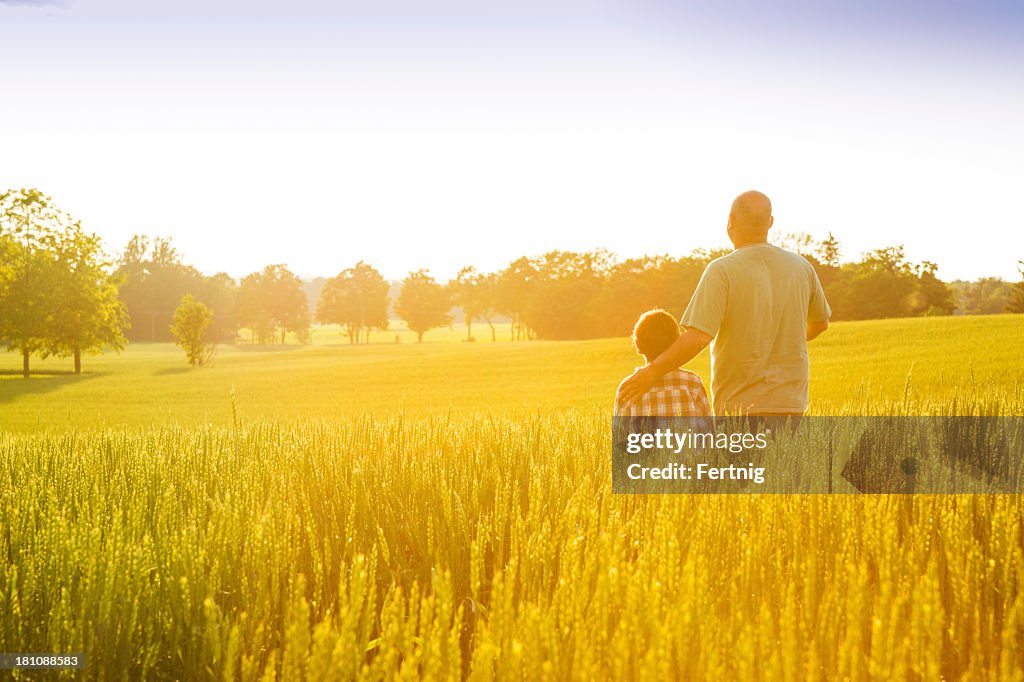 Farmer with his son at sunset