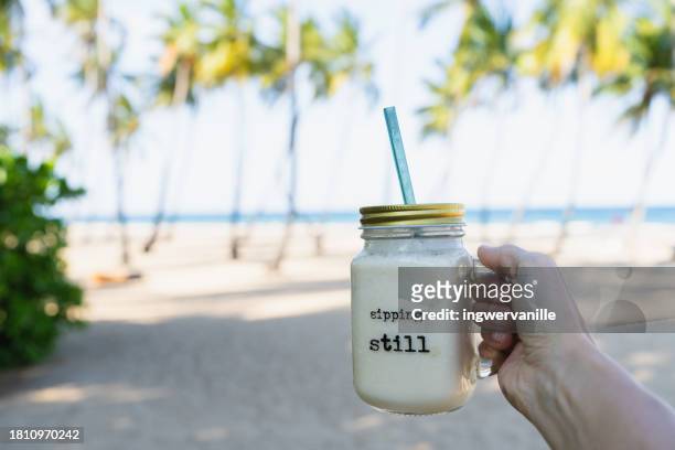 close-up of woman holding white smoothie at the beach - smoothie close up textfreiraum stock-fotos und bilder