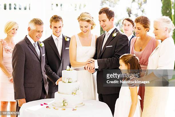 guests looking at bride and groom cutting cake during reception - wedding cake cutting stockfoto's en -beelden