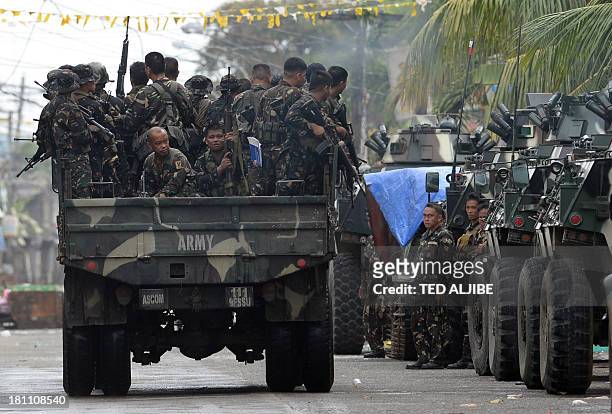 Military truck loaded with soldiers speed past armored personnel carrier near the site of a stand-off as firefighting between government troops and...