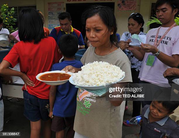 Woman carries her food rations at an evacuation center near the site of a stand-off at an evacuation center in the city of Zamboanga on the southern...