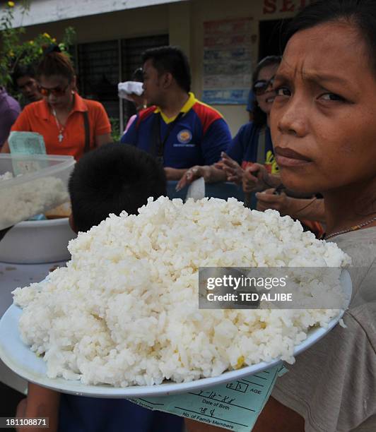 Woman carries her food rations at an evacuation center near the site of a stand-off at an evacuation center in the city of Zamboanga on the southern...