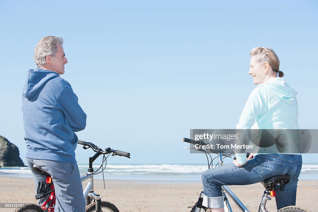 Um casal sentado na bicicleta na praia