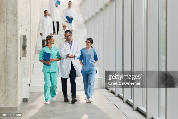 happy medical experts talking on the move in a hospital. - doctor on the move stock pictures, royalty-free photos & images