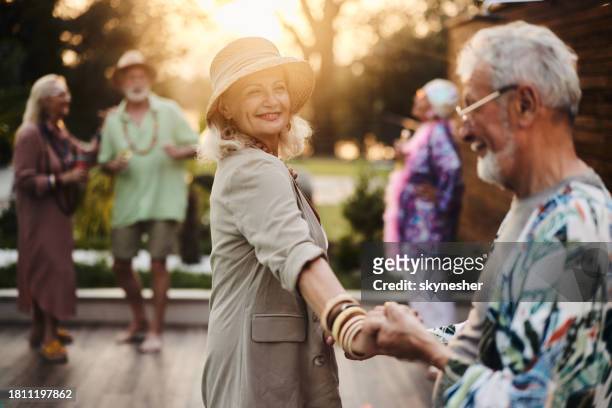 happy mature couple dancing on a party in the backyard at sunset. - retirement party stock pictures, royalty-free photos & images