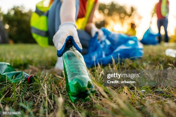 young female nature conservation volunteer picking up trash in the nature - taking off gloves stock pictures, royalty-free photos & images