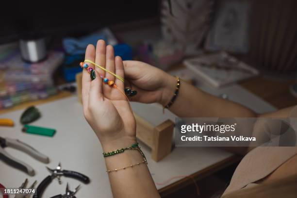 over shoulder view of female artisan hands with bracelets crafting multicolored bead necklace - white bead stock pictures, royalty-free photos & images