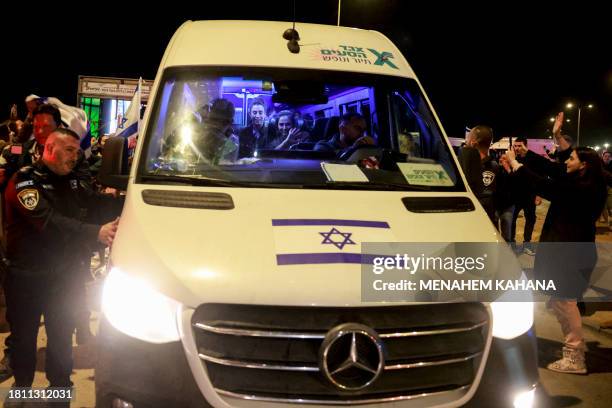 Supporters welcome Israeli hostages as they arrive in a vehicle at Ofakim army base in southern Israel early on November 30 after being freed from...