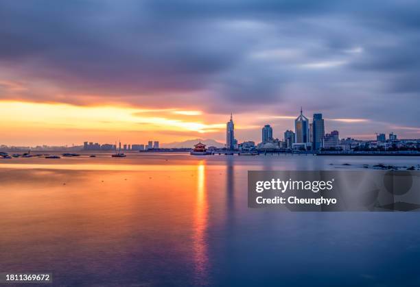 zhanqiao pier and city skyline against dramatic sky in qingdao, shandong province, china - storm cloud sun stock pictures, royalty-free photos & images