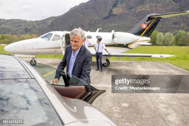 chauffeur opening car door, private jet in the background - car door stock pictures, royalty-free photos & images