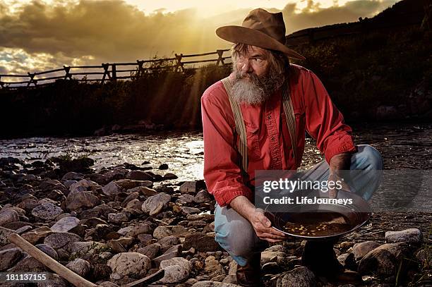 old prospector panning for gold in a western sunset - gold panning stock pictures, royalty-free photos & images