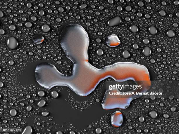 large drop of silver colored liquid on a surface of small water droplets. - couronne d'eau photos et images de collection