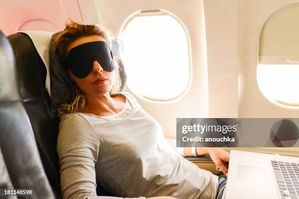 mature woman having nap in a plane - computer wearing eye mask stock pictures, royalty-free photos & images