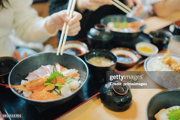 group of tourist eating premium fresh raw seafood mixed rice bowl kaisen-donjapanese rice with sashimi of tuna, maguro, otoro, salmon, squid and ikura (salmon eggs) - ikura stock pictures, royalty-free photos & images