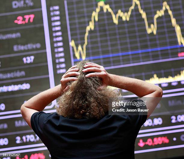 Desperate equity trader in front of a display panel of the Madrid stock exchange in the trading room.