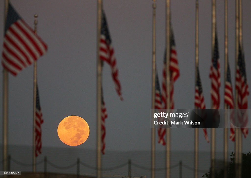 Full Moon Sets Behind Flags Lowered To Half Staff