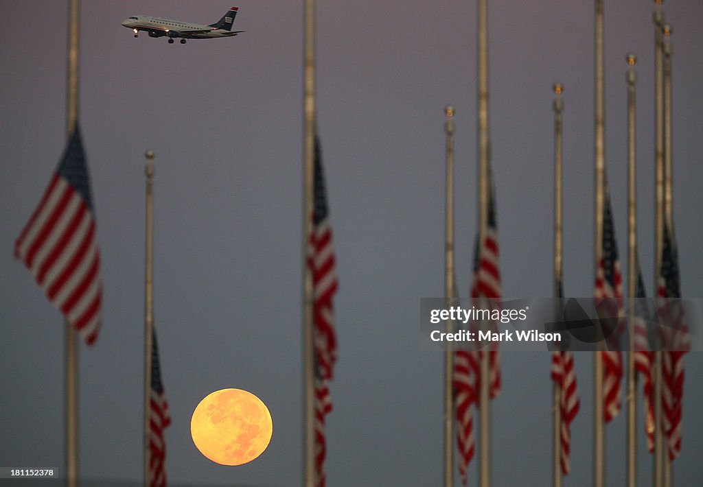 Full Moon Sets Behind Flags Lowered To Half Staff