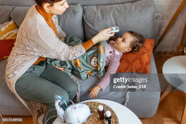 mother examining a body temperature to her daughter. - serbia covid stock pictures, royalty-free photos & images