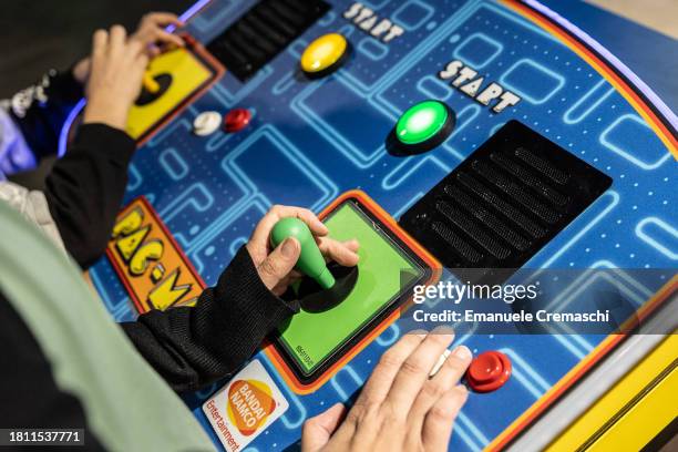 Child and a woman handle two joysticks while playing a vintage "Pac - Man" video game during Milan Games Week 2023 at Rho Fieramilano on November 24,...
