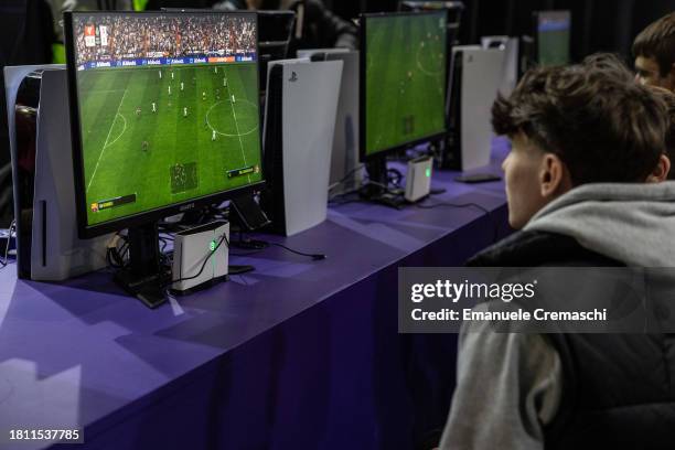 Fairgoers play EA Sports' FC 24 video game for Playstation at the Italian digital bank isybank display stand during Milan Games Week 2023 at Rho...