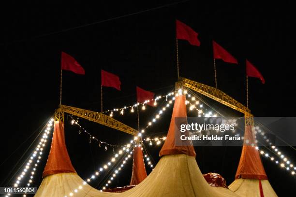 night view from the top of a circus tent adorned with red flags and strings of lamps - zirkus stock-fotos und bilder