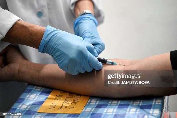 In this photo taken on October 6 shows a doctor extracting blood from a patient for HIV testing at a community center in Iloilo. The spread of HIV...