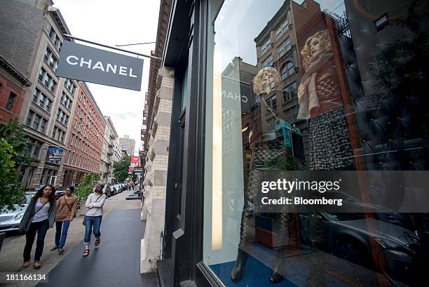 Shoppers stroll past mannequins in the window of a Chanel SA store in the shopping district of Soho in New York, U.S., on Saturday, Sept. 14, 2013....